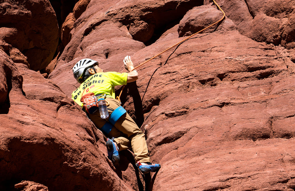 コバさんがナオヤさんの声を頼りにユタ州の真っ赤な砂岩を登る様子