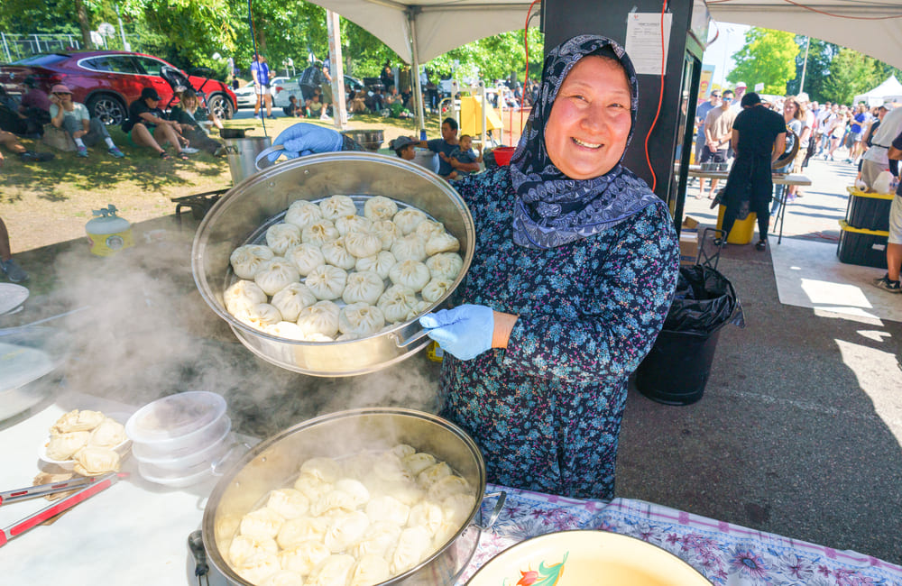 蒸した大量の餃子を見せる女性